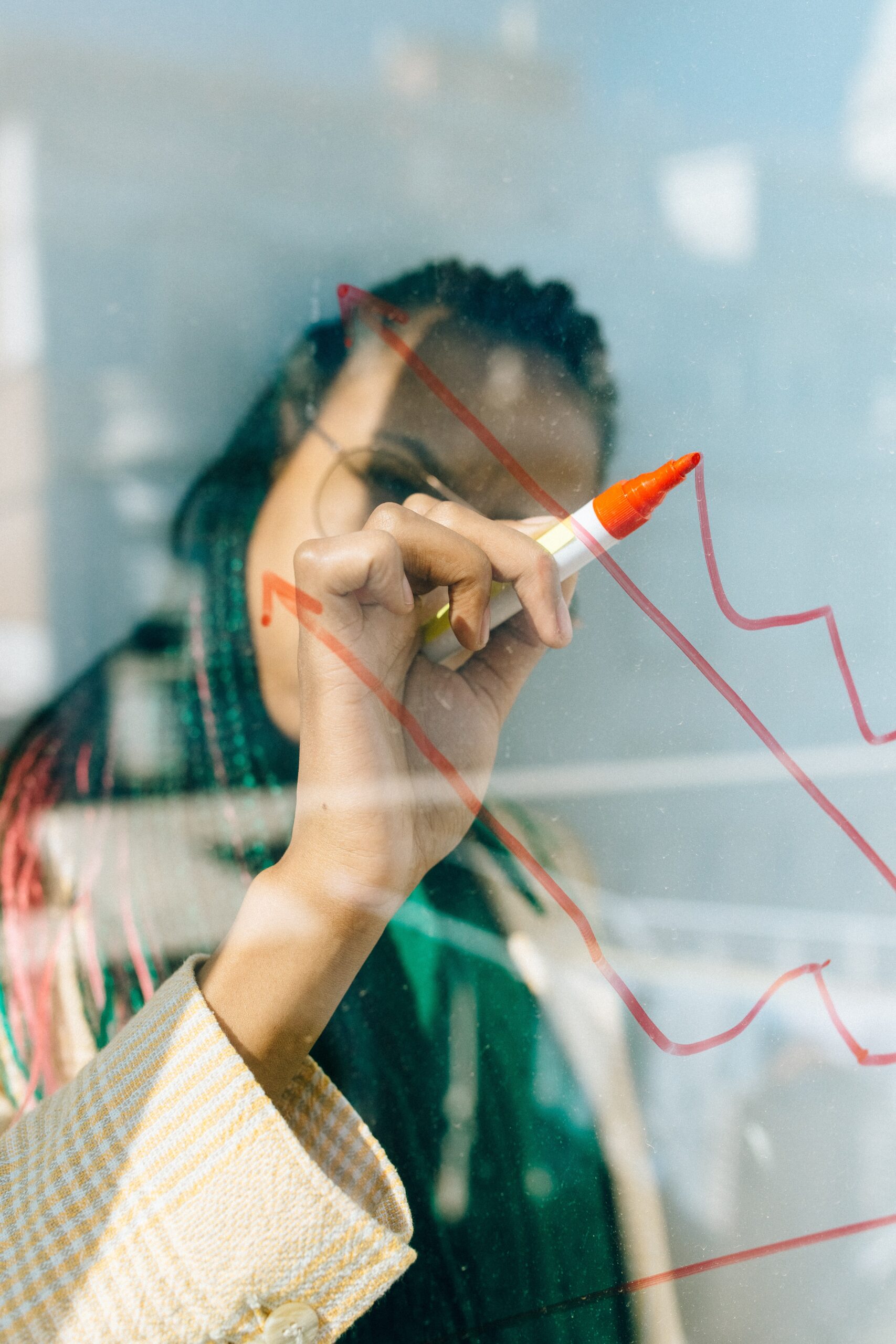 woman drawing a chart with marker on a clear plexi board.